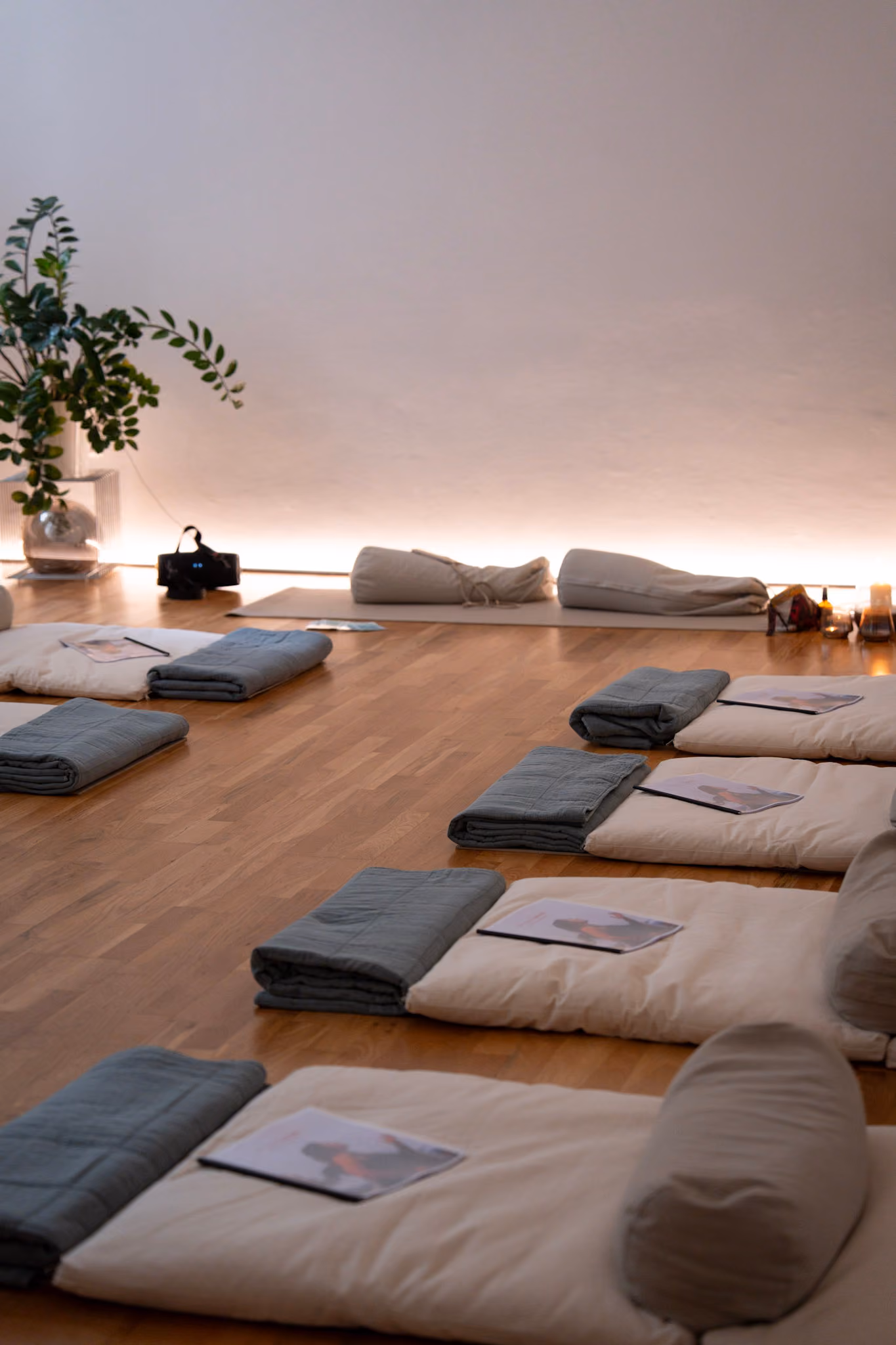 Der Ausbildungsraum vor einer Runde: Matten mit Decken und aufgelegten Workbooks, warmes Licht an der Wand